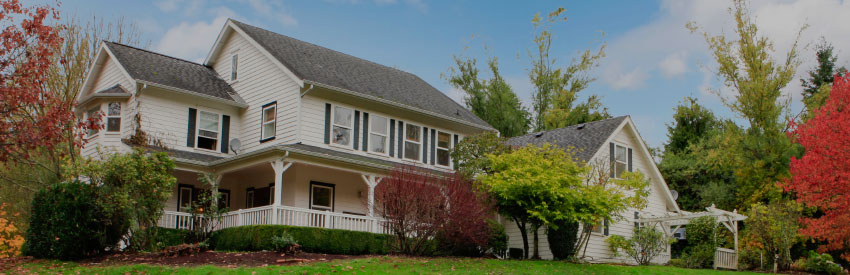 A very nice large white house with a nice yard and beautiful trees